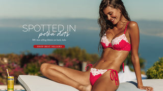 Model wearing a red polka dot bikini sitting on a ledge. 