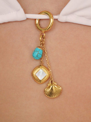 Gold charm with turquoise stone and shell pendant on a white bikini top