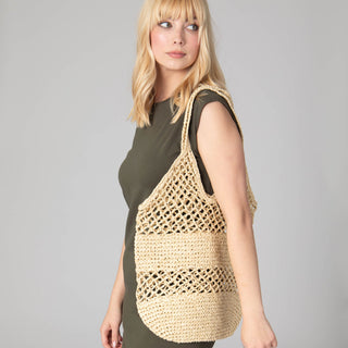 Model carrying a tan crochet tote bag. 