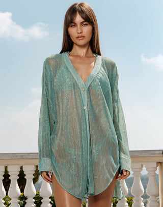 Woman wearing a light green sheer cover-up against a blue sky.