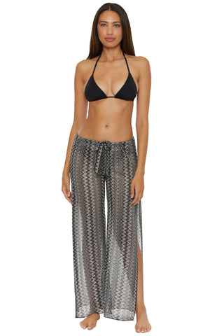 Woman wearing a black bikini top and patterned pants on a white background