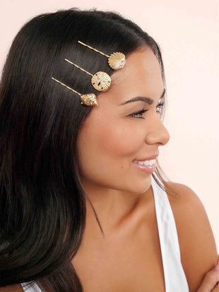 Woman with gold hair accessories in her hair against a beige background