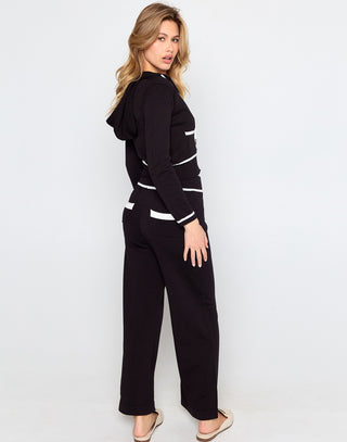 Woman wearing a black outfit with white accents on a light gray background