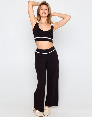 Woman wearing a black sports bra and high-waisted black pants on a white background