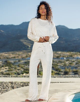 Woman in a white outfit standing in a desert landscape with mountains in the background