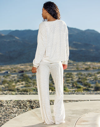 Person wearing a white outfit standing on a rooftop with mountains in the background