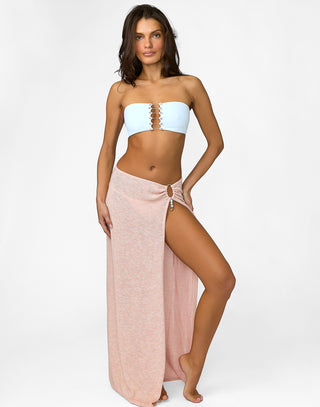 Woman wearing a light blue strapless top and pink skirt on a white background