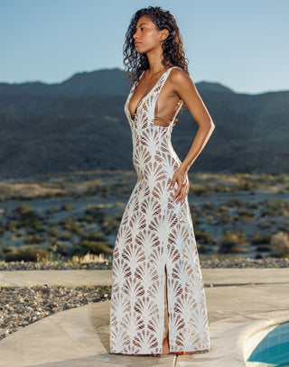 Woman in a white lace dress standing in a desert landscape with mountains in the background