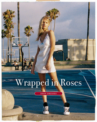 Model wearing a white mini dress with embroidered rose details. Shop dresses. 